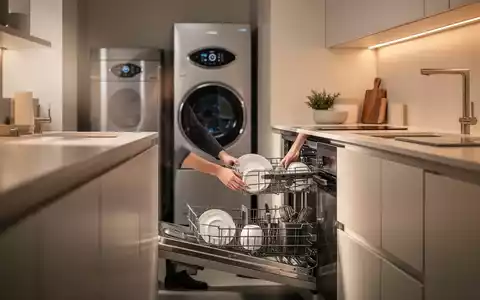Eine moderne, energieeffiziente Küche mit einem Wärmepumpentrockner und einer Person, die eine Spülmaschine belädt. - Foto: über boerse-global.de