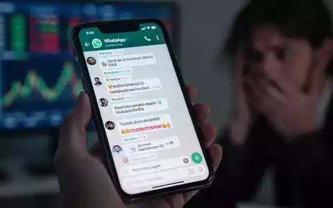 Nahaufnahme eines Smartphones mit einem verdächtigen WhatsApp-Gruppenchat, gehalten von einer Person, die Sorge ausdrückt. - Foto: über boerse-global.de