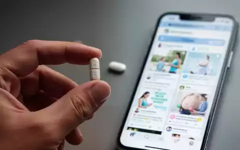 Eine Hand hält eine Pille, im unscharfen Hintergrund sind Social-Media-Feeds auf einem Smartphone zu sehen, die sich auf Gesundheit und Wellness beziehen. - Foto: über boerse-global.de