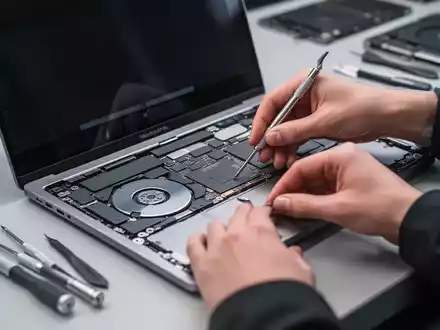 Nahaufnahme eines reparierten MacBook Pro mit sichtbaren Händen und Werkzeugen eines Technikers, Fokus auf die internen Komponenten. - Foto: über boerse-global.de