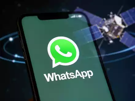 Ein Smartphone-Bildschirm zeigt das WhatsApp-Logo, im Hintergrund ein Satellit, der globale Satellitenkommunikation symbolisiert. - Foto: über boerse-global.de