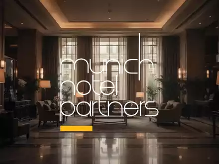 Eine gedämpfte, elegante Hotellobby mit weichem, warmem Licht, das durch große Fenster fällt, suggeriert ruhigen Luxus und verhaltenen Optimismus. - Foto: über boerse-global.de
