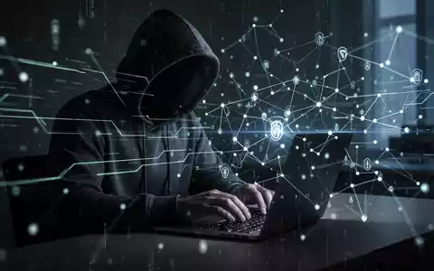 Eine schattenhafte Figur mit Kapuzenpullover tippt auf einem Laptop, umgeben von leuchtenden digitalen Linien und Netzwerkknoten. - Foto: über boerse-global.de