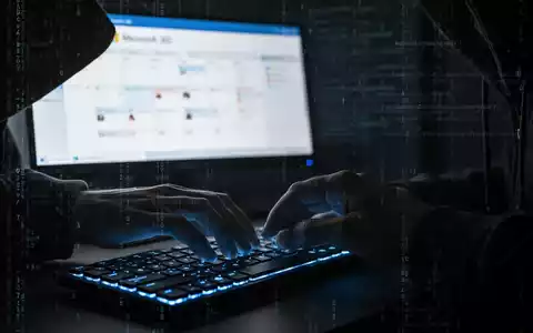 Schattenhafte Hände tippen auf Tastatur, verschwommener Microsoft 365-Kalender und digitale Code-Overlays, die Cyberbedrohungen darstellen. - Foto: über boerse-global.de