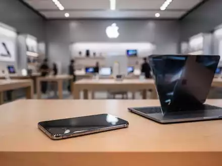 Modernes Smartphone und Laptop auf einem sauberen Tisch in einem eleganten, professionellen Apple Store. - Foto: über boerse-global.de