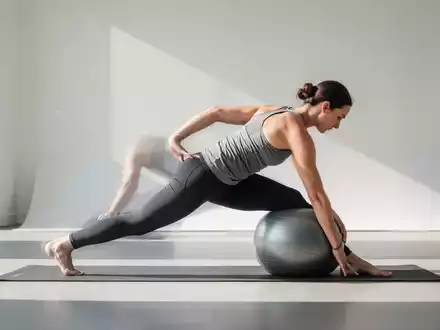 Person beim ganzheitlichen Rückentraining mit einem kleinen Fitnessball in einem modernen Studio. - Foto: über boerse-global.de