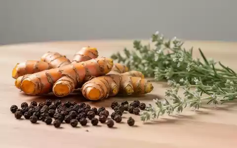 Frische Kurkuma-Wurzeln und schwarze Pfefferkörner auf einem Holztisch als Symbol für natürliche Heilmittel. - Foto: über boerse-global.de