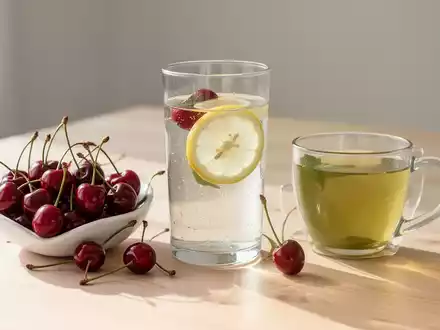 Gesunde Lebensmittel wie Kirschen, Zitronenwasser und grüner Tee auf einem Holztisch als Symbol für natürliche Ernährung. - Foto: über boerse-global.de