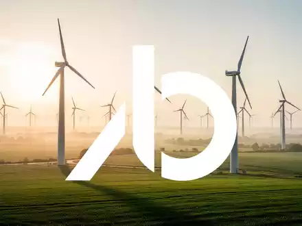 Moderne Windkraftanlagen in einer sonnigen grünen Landschaft bei Sonnenaufgang. - Foto: über boerse-global.de