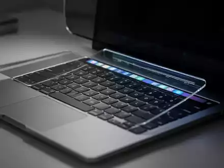 Nahaufnahme einer MacBook Pro-Tastatur und Touch Bar in einem modernen, schwach beleuchteten Büro. - Foto: über boerse-global.de