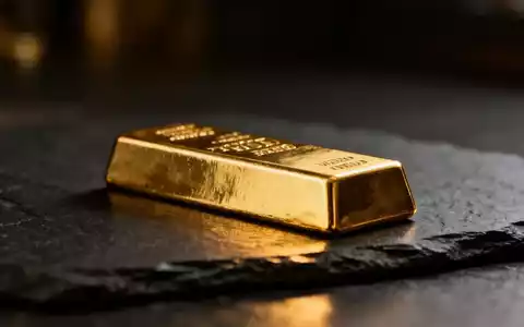 Ein glänzender Goldbarren auf einem dunklen, strukturierten Untergrund bei dramatischem Licht. - Foto: über boerse-global.de