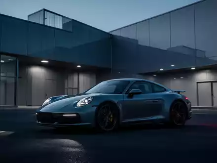 Moderner Porsche Sportwagen vor einer minimalistischen Industrieanlage während der Dämmerung. - Foto: über boerse-global.de