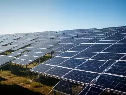 Reihen von Solarmodulen in einem Solarpark bei blauem Himmel. - Foto: über boerse-global.de