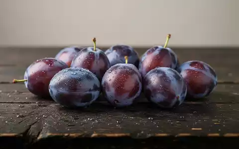 Frische reife Pflaumen mit Tautropfen auf einem dunklen Holztisch in einer professionellen Nahaufnahme. - Foto: über boerse-global.de