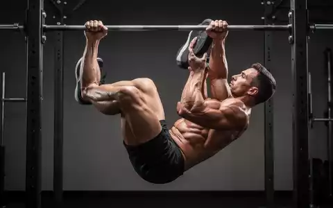 Sportler beim kontrollierten Ausführen von Hanging Leg Raises an einer Klimmzugstange in einem modernen Fitnessstudio. - Foto: über boerse-global.de