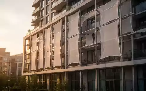 Moderne Wohnhausfassade mit textiler Membrankühlung zur Hitzereduktion an einem sonnigen Tag. - Foto: über boerse-global.de
