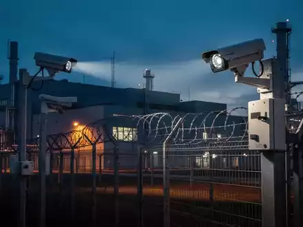 Moderne Sicherheitsanlage eines Rüstungsunternehmens bei Dämmerung mit Fokus auf Überwachungstechnik. - Foto: über boerse-global.de