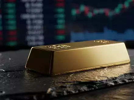 Ein glänzender Goldbarren auf einer dunklen Schieferplatte bei dramatischer Beleuchtung. - Foto: über boerse-global.de