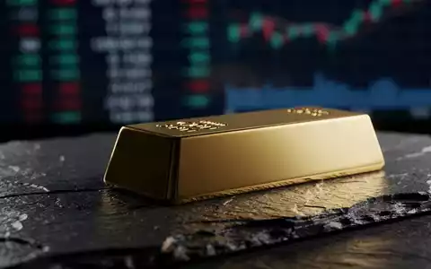 Ein glänzender Goldbarren auf einer dunklen Schieferplatte bei dramatischer Beleuchtung. - Foto: über boerse-global.de