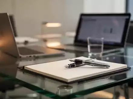 Ein moderner, minimalistischer Schreibtisch in einem Büro mit Laptop und Notizbuch, symbolisch für arbeitsrechtliche Reformen. - Foto: über boerse-global.de