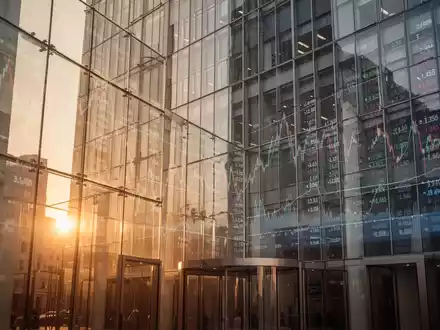 Modernes Börsengebäude mit spiegelnden Glasfronten und angedeuteten Finanzgrafiken bei goldenem Licht. - Foto: über boerse-global.de