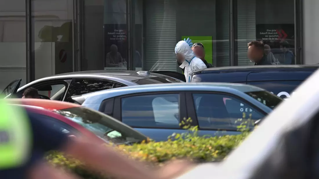 Polizisten führten am Abend einen Mann in einem weißen Anzug aus dem Gebäude, wenig später wurde eine Festnahme vermeldet. - Bild: Armin Weigel/dpa