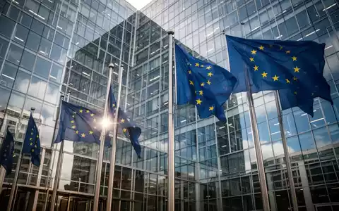 Europäische Flaggen vor einem modernen Bürogebäude als Symbol für regulatorische Eingriffe der EU-Kommission. - Foto: über boerse-global.de