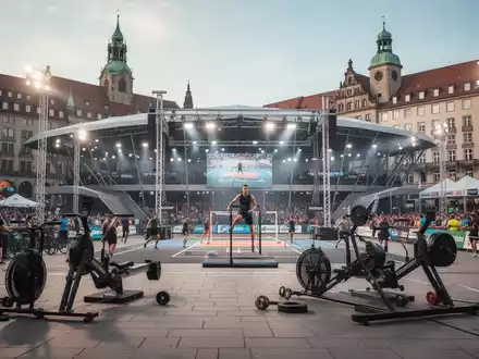 Sportliche Wettkampfstätte auf einem belebten Stadtplatz mit moderner Arena-Architektur vor historischer Kulisse. - Foto: über boerse-global.de