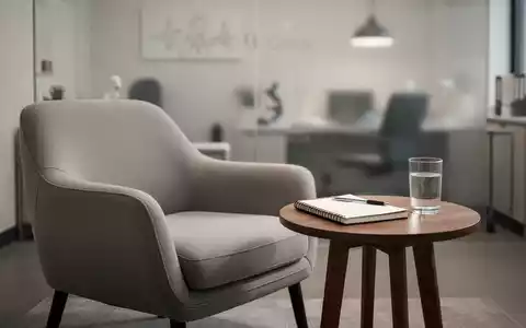 Ein minimalistisch eingerichteter Therapieraum mit einem bequemen Sessel und einem Notizblock, Symbolbild für psychotherapeutische Versorgung. - Foto: über boerse-global.de