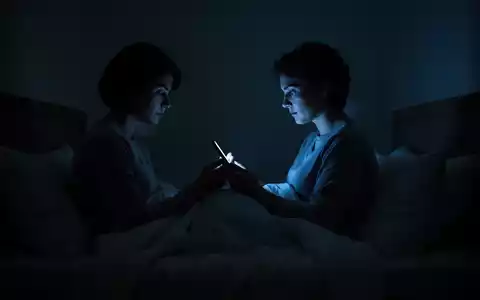 Silhouette einer Person, die nachts im Bett auf das bläuliche Licht ihres Smartphones schaut. - Foto: über boerse-global.de