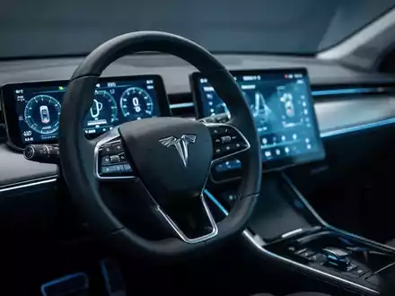 Modernes Armaturenbrett eines Elektroautos mit digitalen Anzeigen und leuchtendem Touchscreen in einer dunklen Umgebung. - Foto: über boerse-global.de