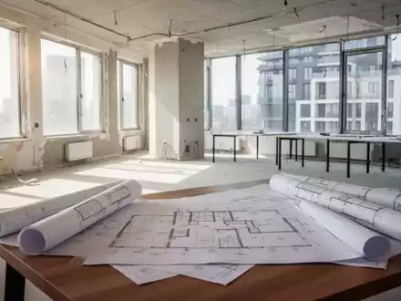 Modernes Bürogebäude im Umbau zu Wohnraum mit Bauplänen im Vordergrund. - Foto: über boerse-global.de
