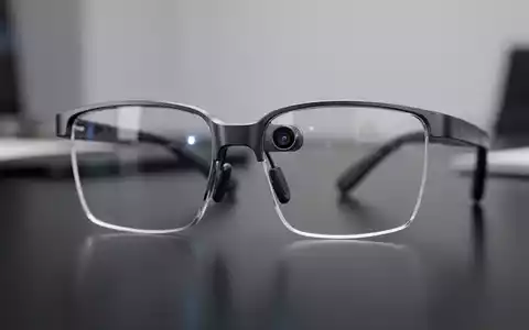 Nahaufnahme einer modernen Smart Brille mit sichtbarer Kameralinse auf einem dunklen Schreibtisch. - Foto: über boerse-global.de