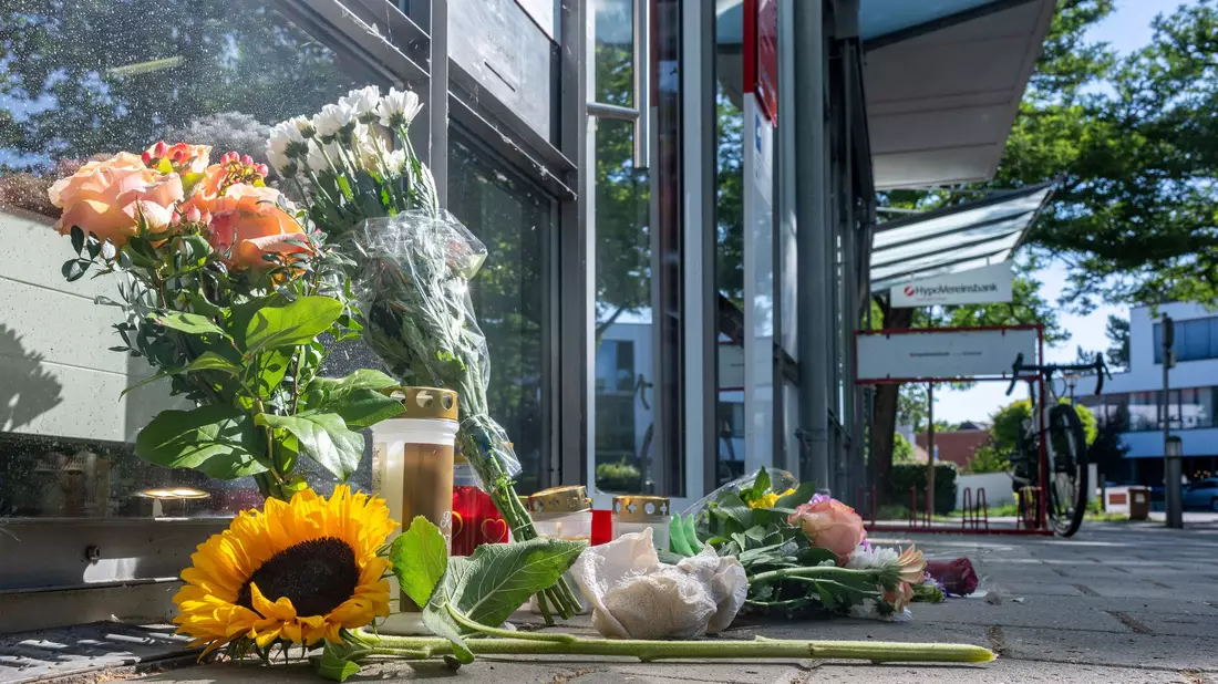 Menschen legten nach dem tödlichen Angriff Blumen und Kerzen vor der Filiale ab. - Bild: Armin Weigel/dpa