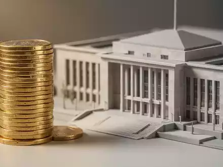 Ein Stapel Euro-Münzen neben einem Modell eines Regierungsgebäudes, das die steigenden Sozialausgaben symbolisiert. - Foto: über boerse-global.de