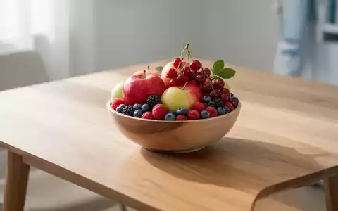 Eine Schale mit frischen Äpfeln und Beeren auf einem Holztisch als Symbol für nierenfreundliche Ernährung. - Foto: über boerse-global.de