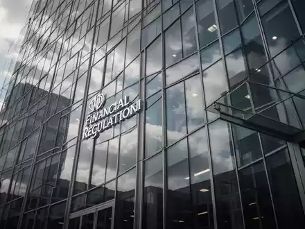 Moderne Glasfassade eines Bürogebäudes unter bewölktem Himmel, symbolisiert Finanzregulierung und Unternehmenskontrolle. - Foto: über boerse-global.de