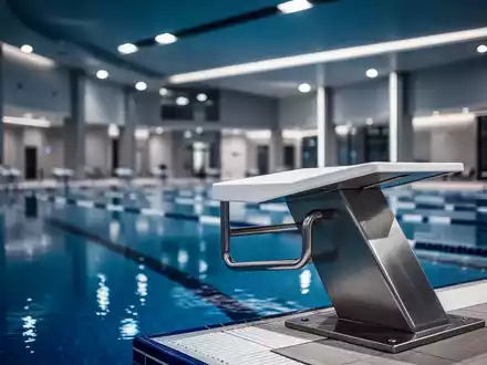 Ein moderner Startblock an einem Schwimmbecken in einer leeren, sanierungsbedürftigen Schwimmhalle. - Foto: über boerse-global.de