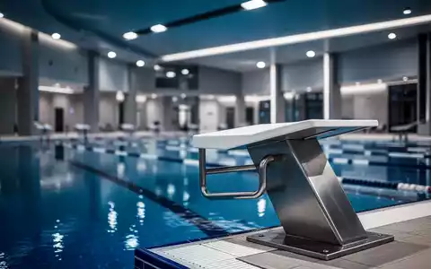 Ein moderner Startblock an einem Schwimmbecken in einer leeren, sanierungsbedürftigen Schwimmhalle. - Foto: über boerse-global.de