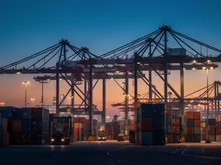 Moderne Hafenanlage mit Containerschiffen und Kränen bei Dämmerung als Symbol für den internationalen Warenhandel. - Foto: über boerse-global.de