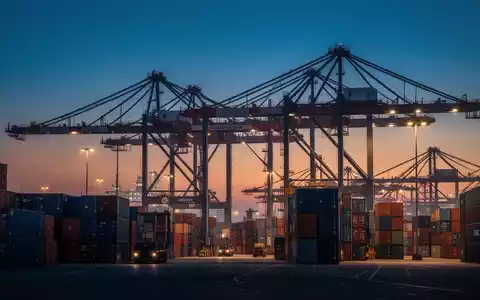 Moderne Hafenanlage mit Containerschiffen und Kränen bei Dämmerung als Symbol für den internationalen Warenhandel. - Foto: über boerse-global.de