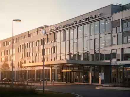 Modernes Klinikgebäude bei Sonnenuntergang als Symbol für die Krankenhausstruktur in Brandenburg. - Foto: über boerse-global.de