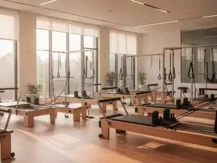 Ein helles, modern eingerichtetes Pilates-Studio mit professionellen Reformer-Geräten in einer ruhigen, minimalistischen Umgebung. - Foto: über boerse-global.de