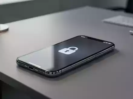 Ein modernes Smartphone auf einem Schreibtisch mit einem digitalen Vorhängeschloss-Symbol als Symbol für Gerätesperren. - Foto: über boerse-global.de