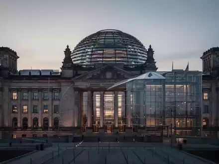 Das Reichstagsgebäude in Berlin bei Dämmerung als Symbol für die politische Neuausrichtung der Bundesregierung. - Foto: über boerse-global.de