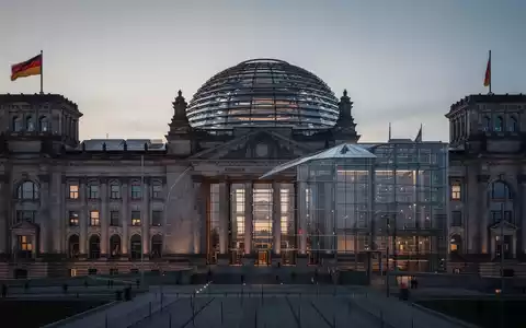 Das Reichstagsgebäude in Berlin bei Dämmerung als Symbol für die politische Neuausrichtung der Bundesregierung. - Foto: über boerse-global.de