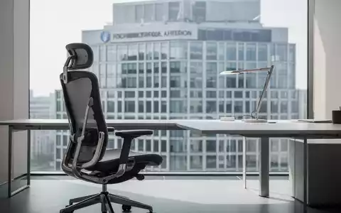 Ein moderner, minimalistischer Büroarbeitsplatz mit einem ergonomischen Bürostuhl vor einer Fensterfront. - Foto: über boerse-global.de
