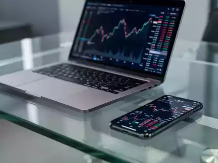 Ein moderner Schreibtisch mit Laptop und Smartphone, das einen Finanzchart anzeigt, symbolisiert den Vanguard ETF. - Foto: über boerse-global.de