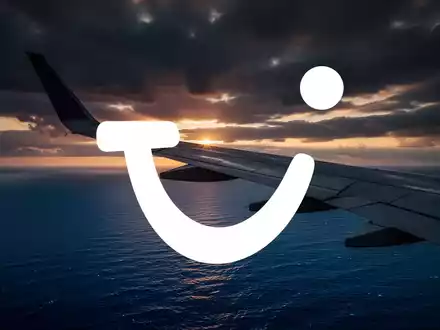 Ein Flugzeugflügel bei Sonnenuntergang über dem Meer als Symbol für die Reise- und Tourismusbranche. - Foto: über boerse-global.de
