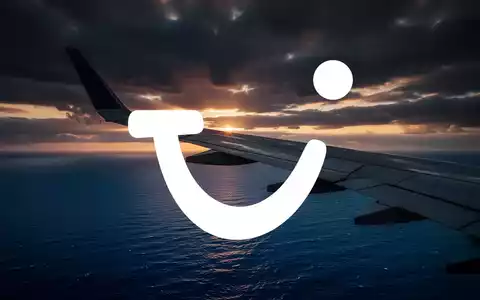 Ein Flugzeugflügel bei Sonnenuntergang über dem Meer als Symbol für die Reise- und Tourismusbranche. - Foto: über boerse-global.de